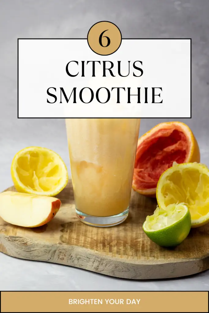 A refreshing citrus smoothie in a glass, surrounded by lemons, oranges, lime, and apple slices on a wooden board.