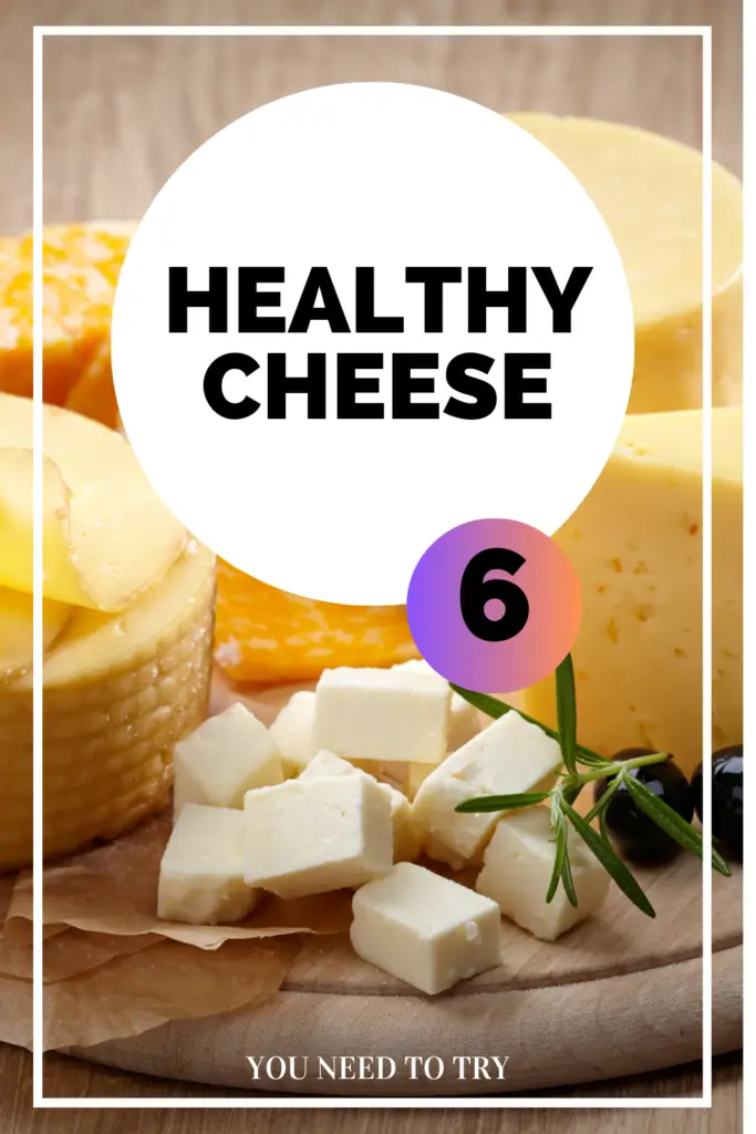 A variety of cheeses displayed on a wooden board, including cubed white cheese and round yellow cheese wheels.