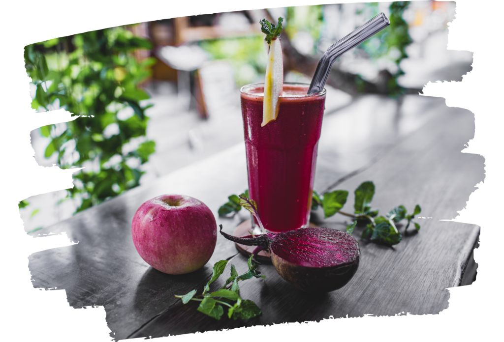 A vibrant apple and beet smoothie with fresh ingredients on a rustic table.