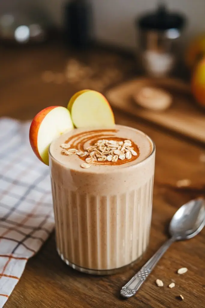 A cinnamon oat apple smoothie served with apple slices and oats.