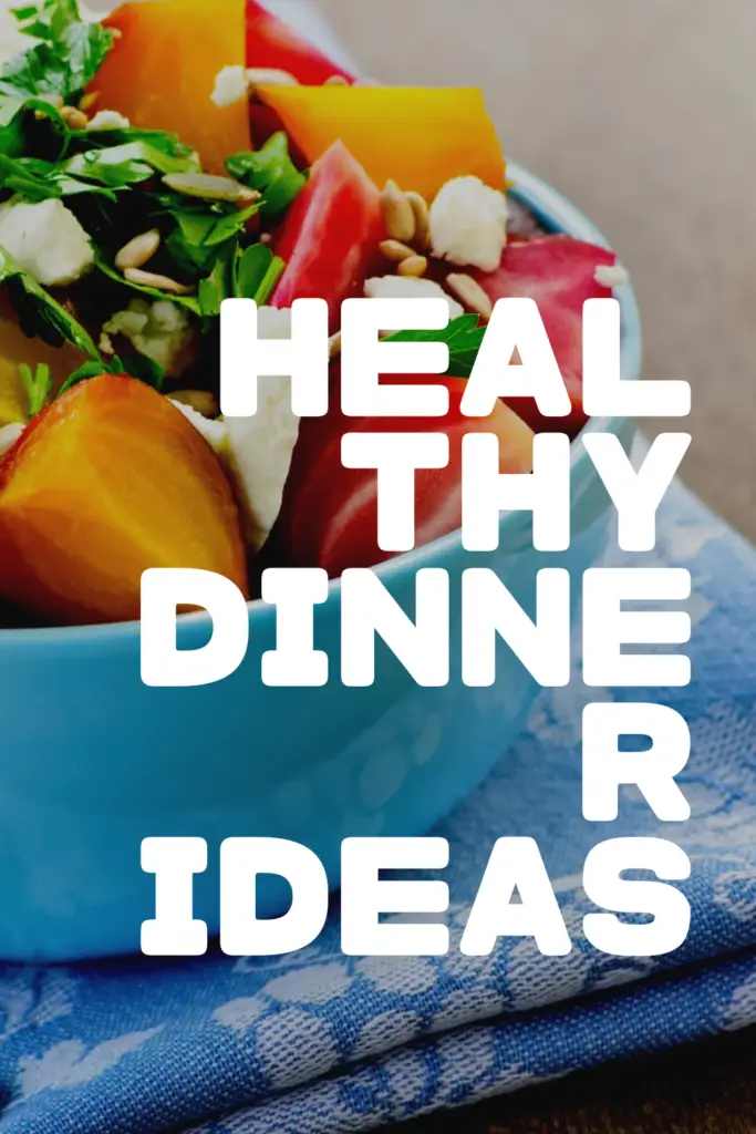 A colorful bowl of salad with vibrant vegetables, fresh greens, and seeds on a blue tablecloth.