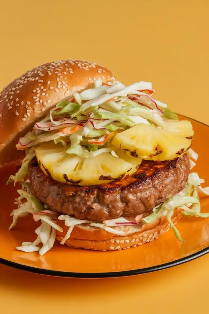 A teriyaki burger topped with grilled pineapple and sesame coleslaw on a sesame seed bun.