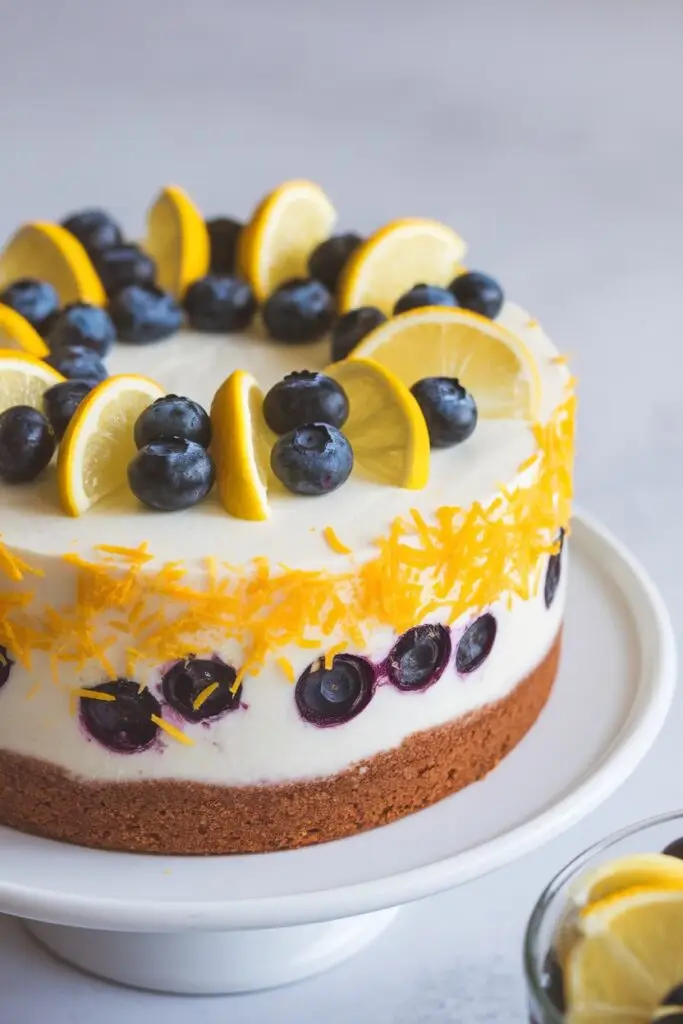 A lemon-infused yogurt blueberry cake decorated with fresh blueberries and lemon slices.