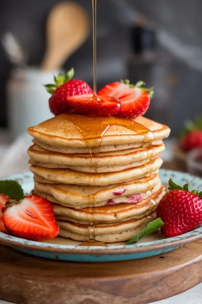 Pancakes topped with strawberries and drizzled with honey.