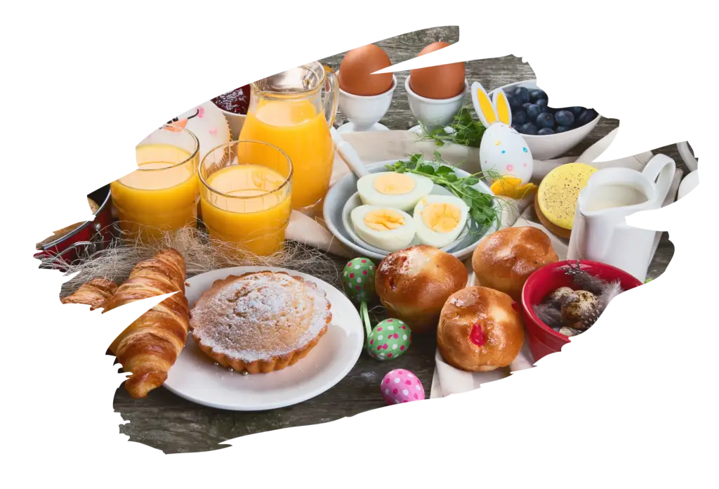 Traditional Easter brunch spread featuring orange juice, croissants, pastries, boiled eggs in egg cups, colorful decorated Easter eggs, and blueberries on a rustic wooden table.