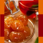 Golden whole fig preserves in a small glass bowl with a mason jar clasp visible in the background, set on a burlap cloth with an amber-colored tea or beverage in a glass cup.