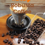 A glass cup of freshly brewed robusta coffee on a wooden surface surrounded by dark coffee beans, offering a bold morning alternative to complement Easter ham recipes for holiday brunches.