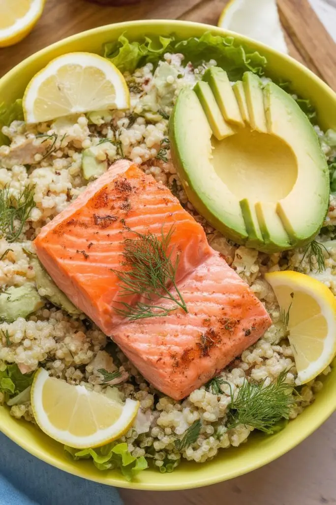 Healthy salmon fillet served with quinoa, fresh dill, half avocado, and lemon slices in a yellow bowl. Easter ham recipes can't compete with this nutritious option!