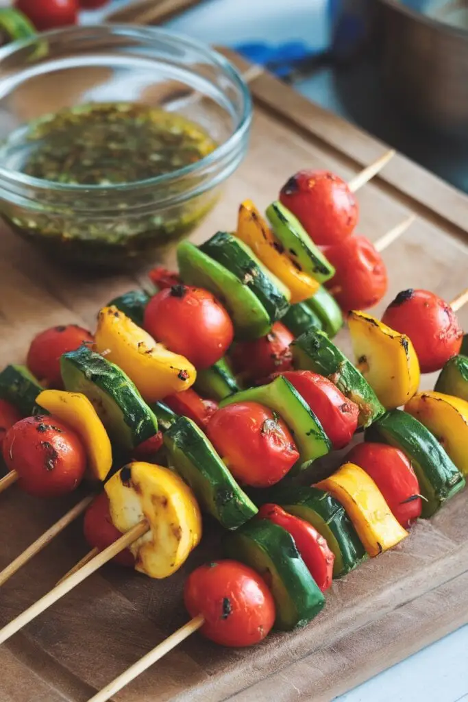 Grilled vegetable skewers with zucchini, bell peppers, and cherry tomatoes, served with a side of dipping sauce.