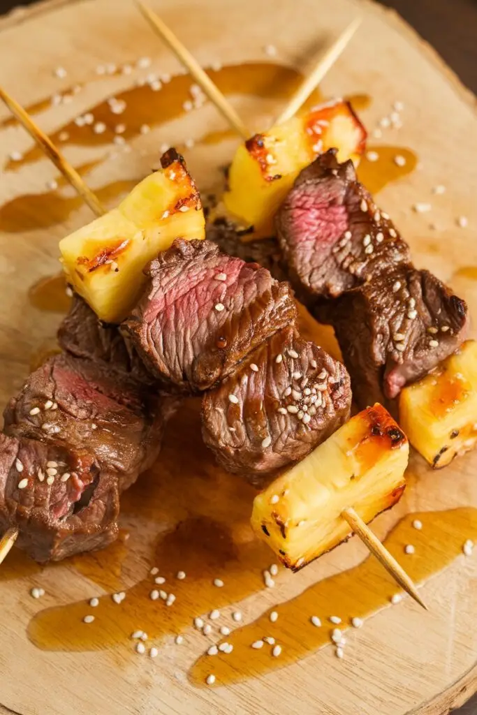 Juicy beef skewers paired with grilled pineapple chunks, garnished with sesame seeds.