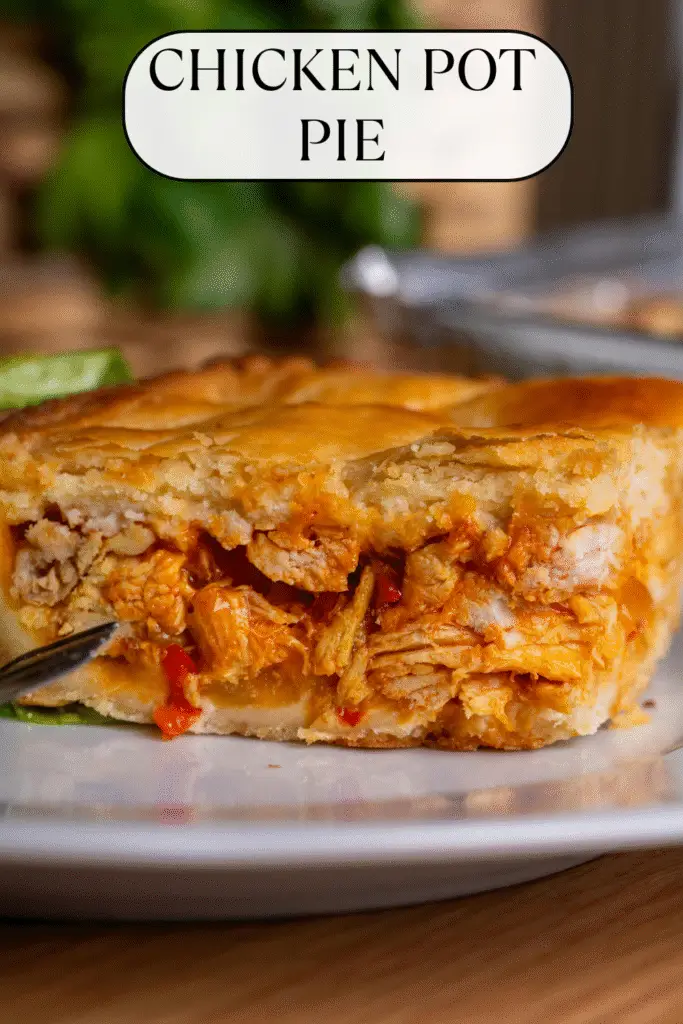 Close-up of a slice of classic chicken pot pie with flaky golden crust and savory filling showing pieces of tender chicken and vegetables.